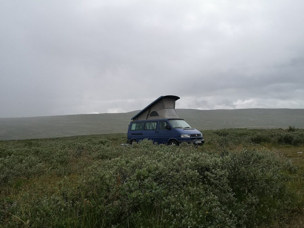 VW T4 Bulli mit Aufstelldach steht frei in der norwegischen Weite unter bewölktem Himmel