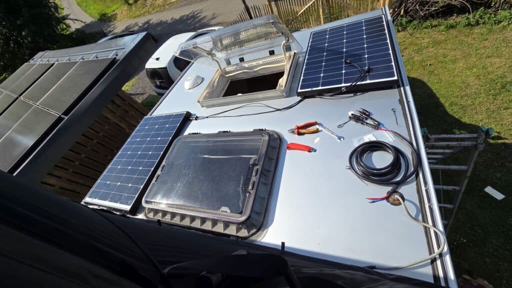 Zwei montierte WATTSTUNDE Solarmodule auf dem Dach der Wohnkabine, daneben Solarkabel, MC4-Stecker und Werkzeug