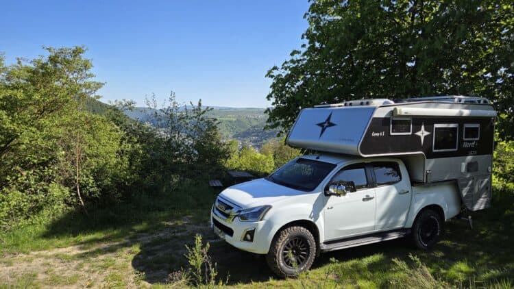 Pickup Camper kaufen: Weißer Isuzu D-Max Double Cab mit grauer Nordstar Camp 6S Wohnkabine auf Aussichtspunkt