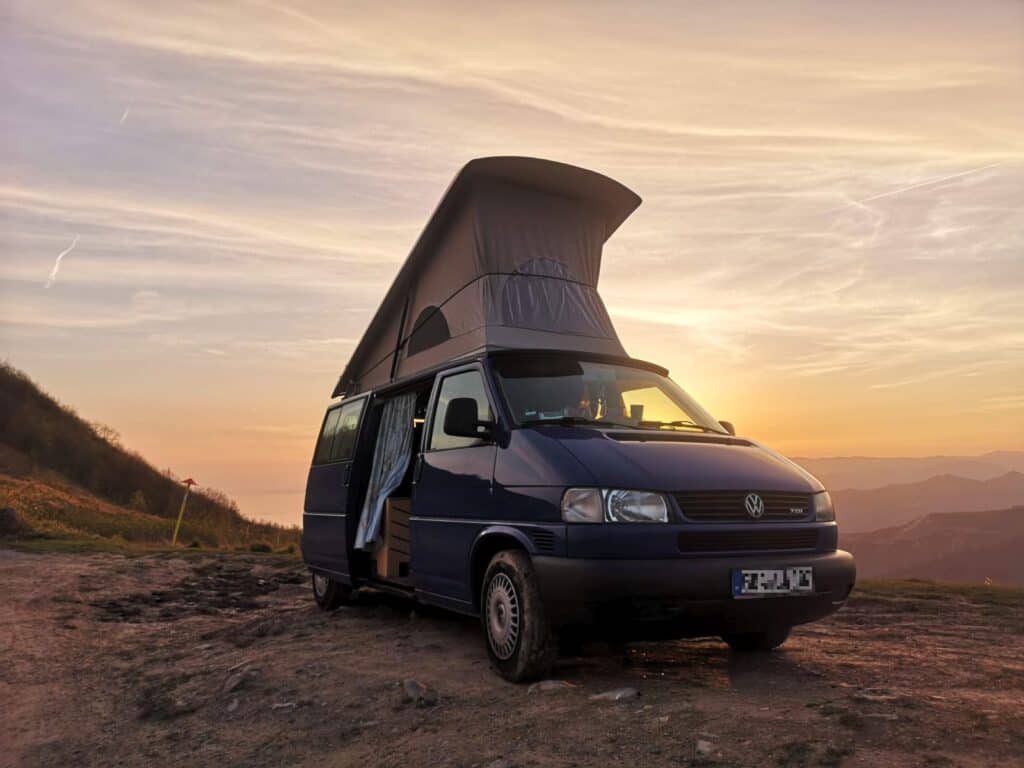 VW T4 Bulli mit Aufstelldach beim Camping im Sonnenuntergang, Familienreisen mit dem Bulli